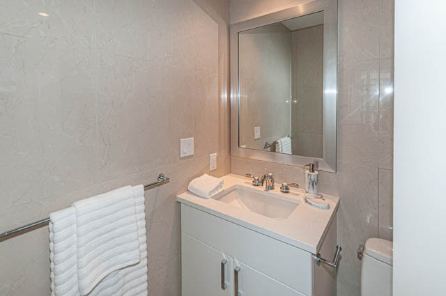 Furnished bathroom with white marble countertops and a large mirror. - 702 - 185 Victory Ship Way, North Vancouver