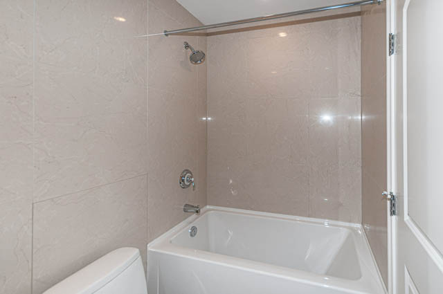 Bright bathroom with marble walls and a modern shower setup. - 702 - 185 Victory Ship Way, North Vancouver