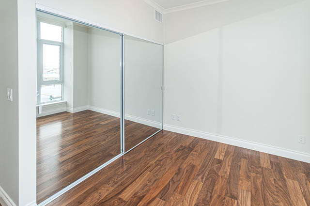 Bright living room with hardwood floors and sliding glass doors leading to a balcony. - 702 - 185 Victory Ship Way, North Vancouver