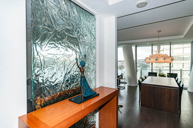 Spacious living room with modern decor, city view, and unique textured wall. - 601 - 1560 Homer Mews, Vancouver Downtown