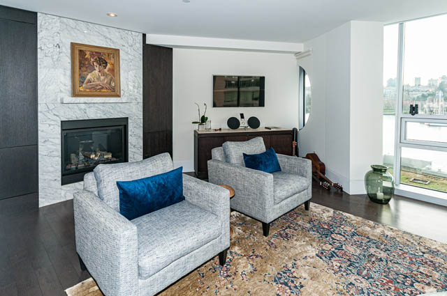 Spacious living room with marble fireplace, city view, and patterned rug. - 601 - 1560 Homer Mews, Vancouver Downtown
