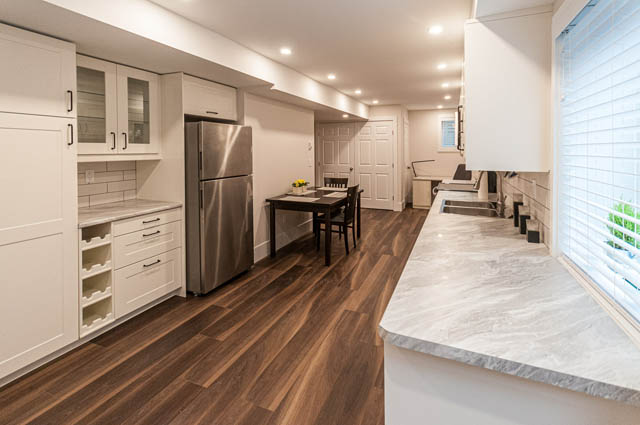 Bright kitchen with white cabinetry, hardwood floors, and a city view. - SUITE - 2806 Munday Place, North Vancouver