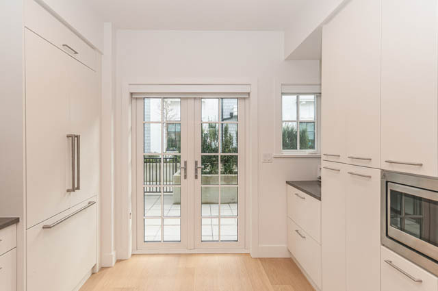 Bright kitchen with white cabinetry, hardwood floors, and a city view. - 9 - 1133 Ridgewood Drive, North Vancouver