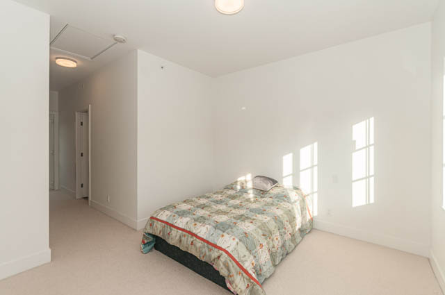 Spacious bedroom with floral bedding and large windows. - 9 - 1133 Ridgewood Drive, North Vancouver