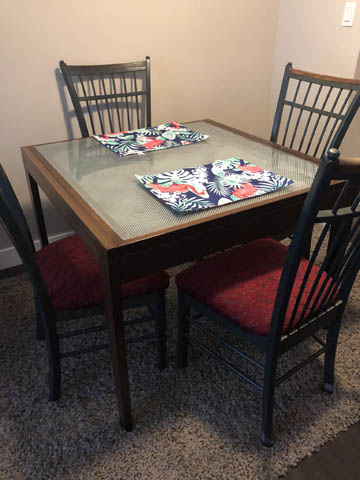 Furnished dining area with glass table, floral placemats, and dark wood chairs. - 111 - 175 1st Street West, North Vancouver