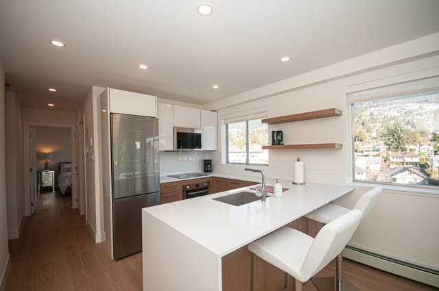 Bright kitchen with white countertops and city view, modern design. - 708 - 150 24th St, West Vancouver
