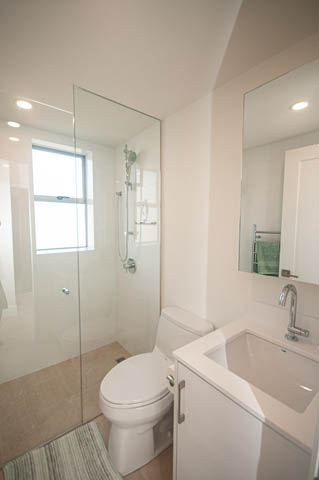 Bright bathroom with white fixtures and a glass shower enclosure. - 708 - 150 24th St, West Vancouver