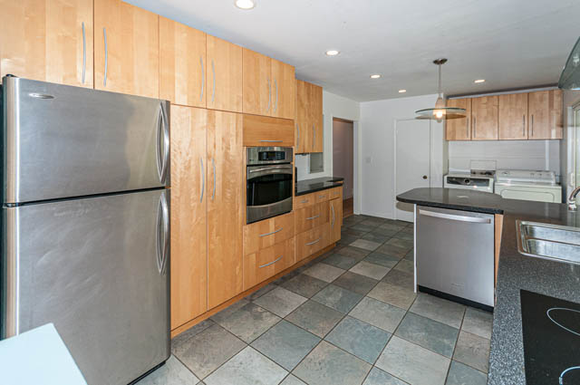 Bright kitchen with granite countertops, stainless steel appliances, and wooden cabinets. - 4037 Ripple Road, West Vancouver