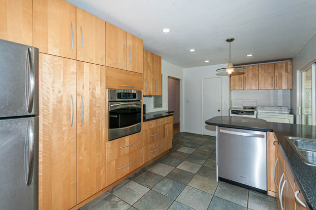 Bright kitchen with wooden cabinets, stainless steel appliances, and granite countertops. - 4037 Ripple Road, West Vancouver
