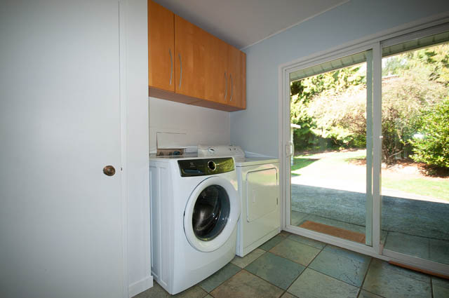 Laundry room with washer, dryer, and wooden cabinets. - 4037 Ripple Road, West Vancouver