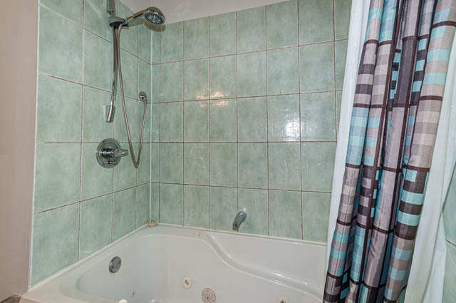 Bathroom with green tiles and shower curtain. - 4037 Ripple Road, West Vancouver