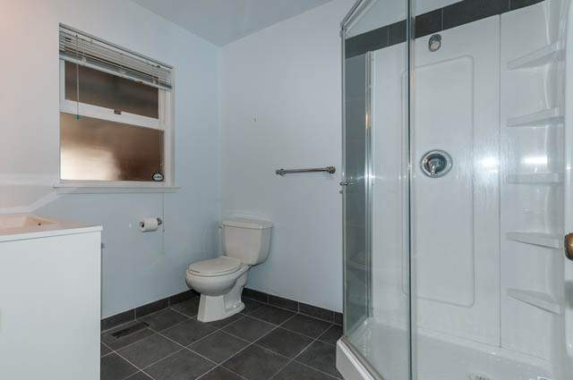 Bathroom with white walls, toilet, shower, and window. - 4037 Ripple Road, West Vancouver