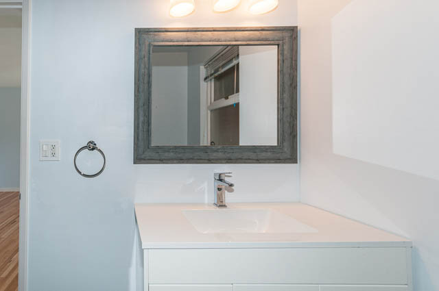 Bright bathroom with white countertop and modern sink, hardwood floors visible. - 4037 Ripple Road, West Vancouver