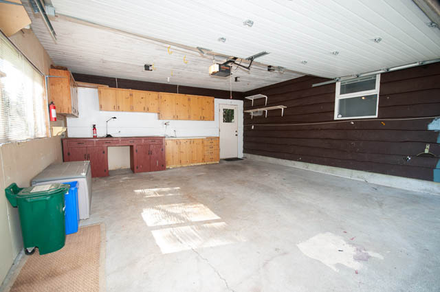 Small, unfinished kitchen with exposed ceiling and brown paneling. - 4037 Ripple Road, West Vancouver