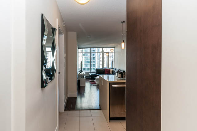 Open-concept living space with modern decor, featuring a kitchen island and city view. - 1607 - 888 Homer St, Vancouver Downtown
