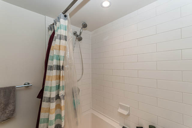 Modern bathroom with white subway tiles and a colorful shower curtain. - 1607 - 888 Homer St, Vancouver Downtown