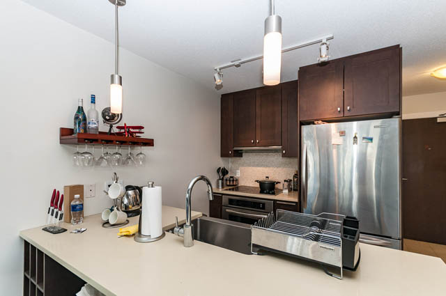 Bright kitchen with modern stainless steel appliances and dark wood cabinets, perfect for a cozy downtown condo.