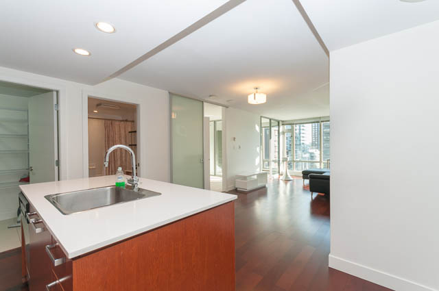 Bright kitchen with white countertops and hardwood floors, leading to a spacious living area with a city view.
