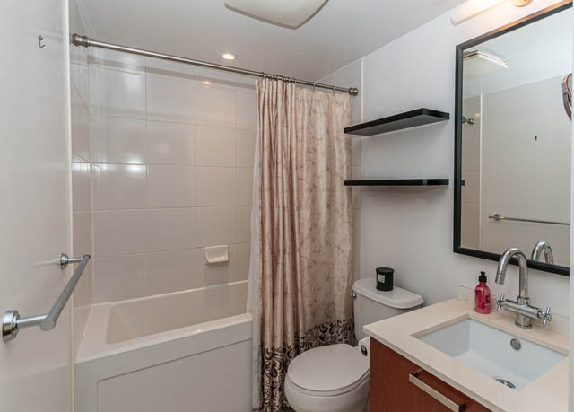Compact bathroom with white tile, modern sink, and black floating shelves. - 903 -1255 Seymour St, Vancouver Downtown