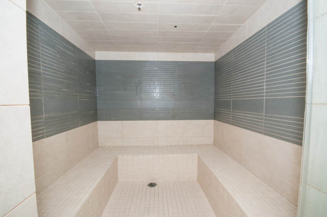 Spacious, modern steam room with tiered seating and dark accent tiles. - 903 -1255 Seymour St, Vancouver Downtown