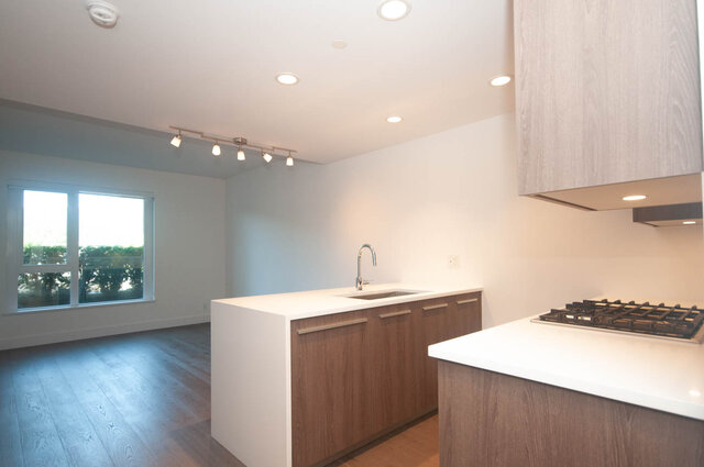 The kitchen features wooden cabinets, white countertops, a stainless steel faucet, a gas stove, and a window with an outdoor 