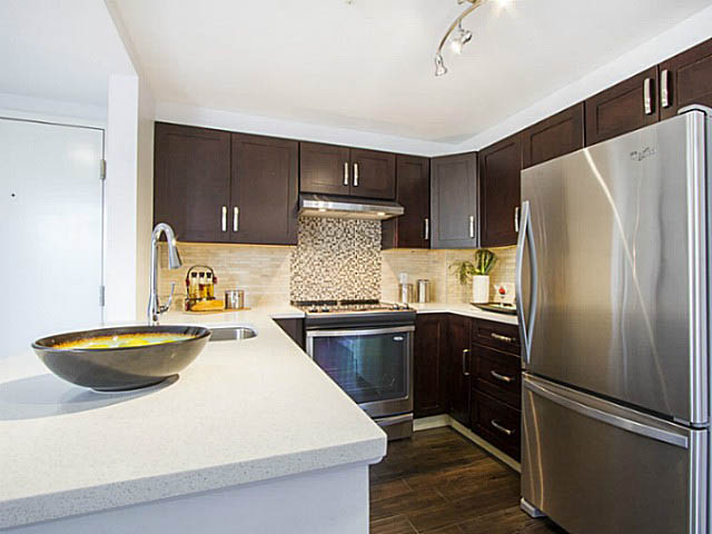 Modern kitchen with granite countertops, stainless steel appliances, and dark wood cabinets. - 606 - 907 Beach Ave, Vancouver Downtown