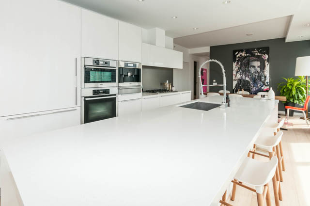 Bright kitchen with white countertops and modern appliances, open to dining area with wooden chairs. - 1101 - 1661 Ontario Street, Vancouver West Side