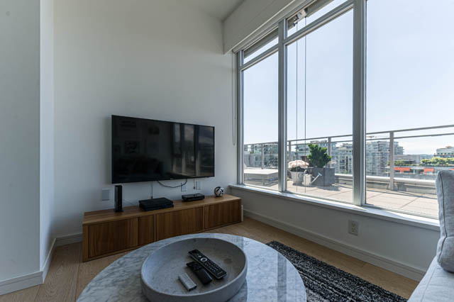 Bright living room with large windows offering a city view and modern furnishings. - 1101 - 1661 Ontario Street, Vancouver West Side