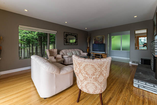 Spacious living room with hardwood floors, large windows, and a cozy sofa set. - 1249 Nepal Crescent, West Vancouver