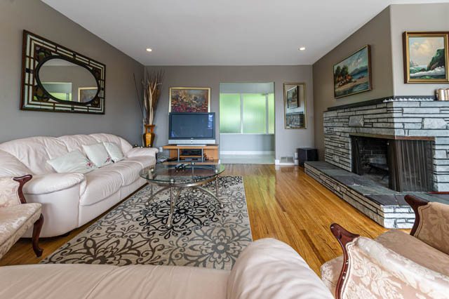 Spacious living room with a fireplace, hardwood floors, and a large window. - 1249 Nepal Crescent, West Vancouver