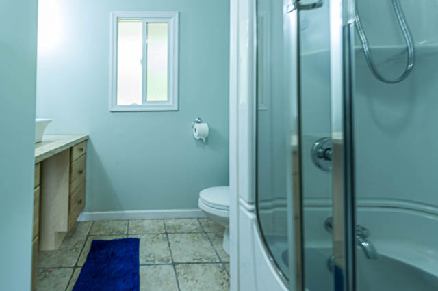 Furnished bathroom with wooden vanity, tiled floor, and shower. - 1249 Nepal Crescent, West Vancouver