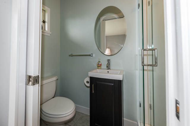 Bright bathroom with white fixtures and a round mirror. - 1249 Nepal Crescent, West Vancouver