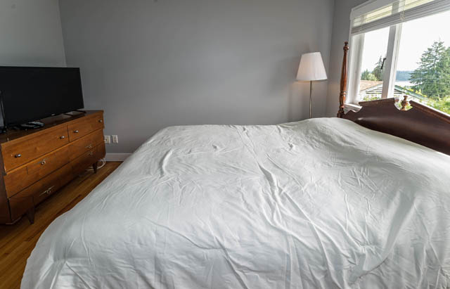 Bright bedroom with hardwood floors, city view, and neatly made bed. - 1249 Nepal Crescent, West Vancouver