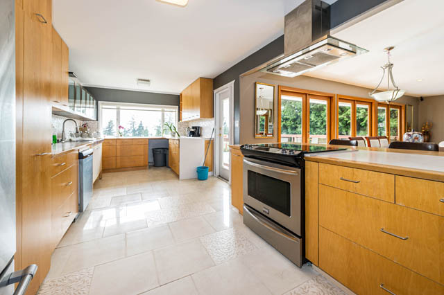 Bright kitchen with light wood cabinets, granite countertops, and a city view. - 1249 Nepal Crescent, West Vancouver