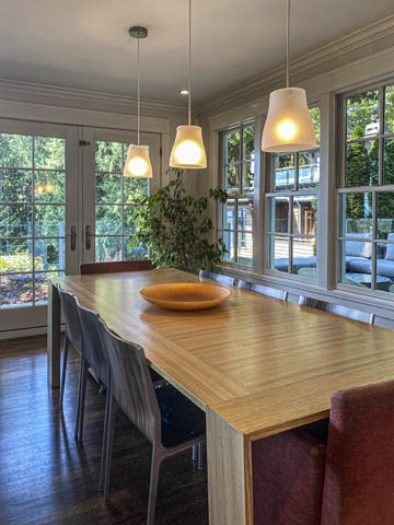 Furnished dining area with hardwood floors, large windows, and pendant lights. - 235 Maple Lane, West Vancouver