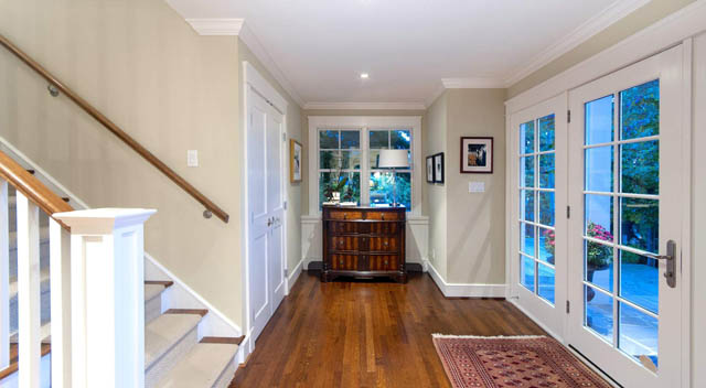 Bright hallway leading to living area with hardwood floors and large windows showing a city view. - 235 Maple Lane, West Vancouver