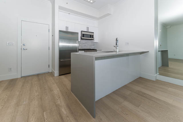 Bright kitchen with light wood floors and modern white cabinetry. - 3205 - 928 Richards St, Vancouver Downtown