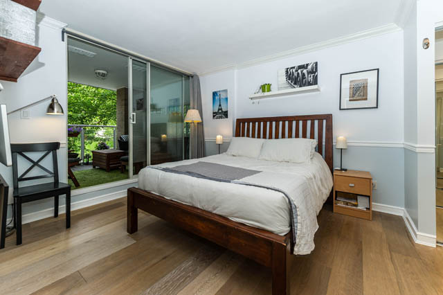 Spacious bedroom with hardwood floors, large sliding glass doors, and a cozy bed setup. - 409 - 1500 Hornby Street, Vancouver Downtown