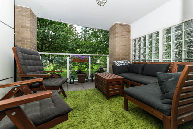 Spacious balcony with green carpet, wooden furniture, and glass block wall, perfect for relaxation. - 409 - 1500 Hornby Street, Vancouver Downtown