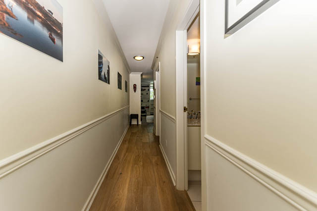 Spacious hallway with hardwood floors and framed artwork, leading to a well-lit bathroom. - 409 - 1500 Hornby Street, Vancouver Downtown