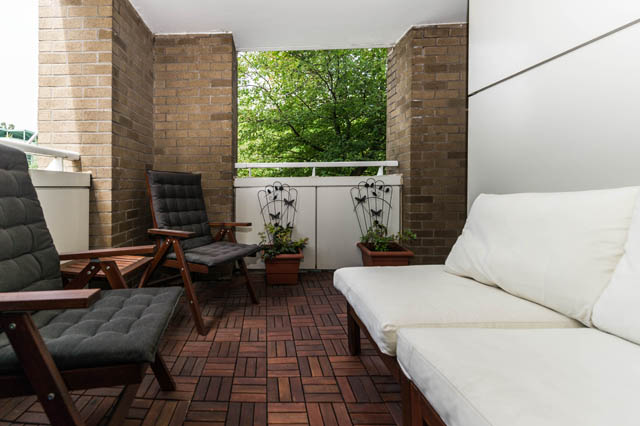 Furnished balcony with wooden deck, white cushioned seating, and potted plants. - 409 - 1500 Hornby Street, Vancouver Downtown