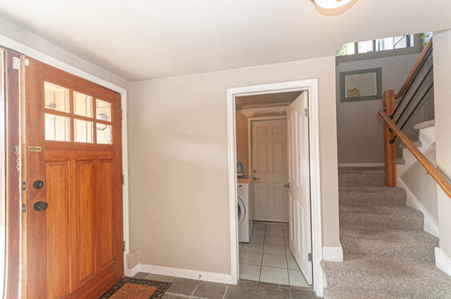 Narrow entryway leading to a tiled floor, wooden doors, and a staircase with carpeted steps. - 85 Glenmore Drive, West Vancouver