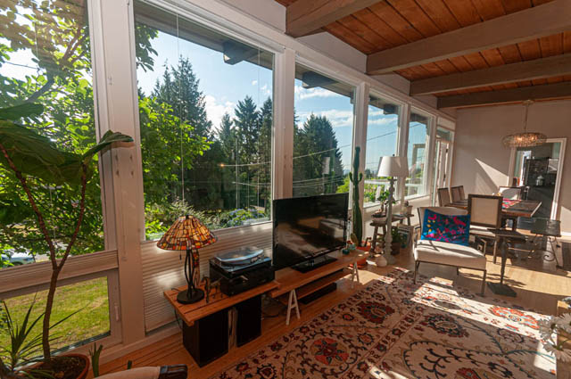 Bright sunroom with large windows, hardwood floors, and a view of lush greenery. - 85 Glenmore Drive, West Vancouver