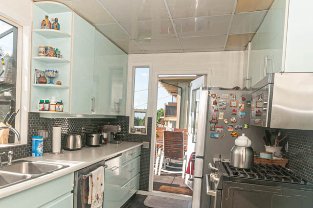 Bright kitchen with light blue cabinets, stainless steel appliances, and black subway tile backsplash. - 85 Glenmore Drive, West Vancouver