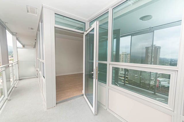 Bright balcony with large windows and city view, featuring white walls and wooden flooring. - 1105 - 125 E 14th St, North Vancouver