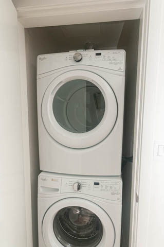 Bright laundry room with stacked washer and dryer, white walls and trim. - 1105 - 125 E 14th St, North Vancouver