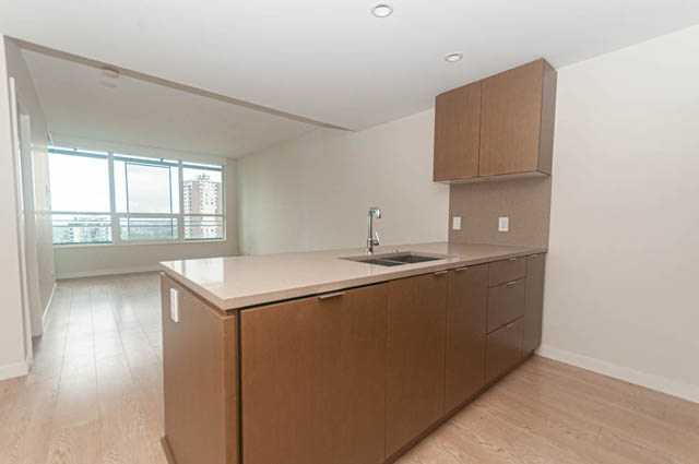 Bright kitchen with wooden cabinets, light countertops, and hardwood floors, featuring a city view. - 1105 - 125 E 14th St, North Vancouver