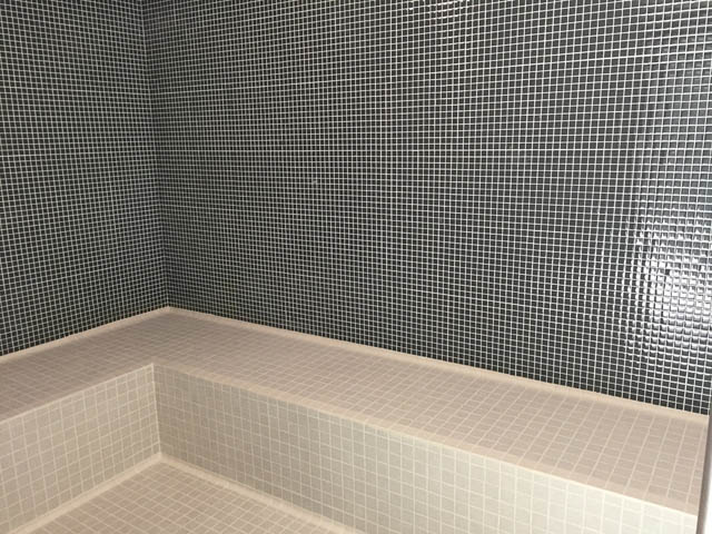 Furnished bathroom with mosaic tile walls and steps leading to a shower area. - 1105 - 125 E 14th St, North Vancouver
