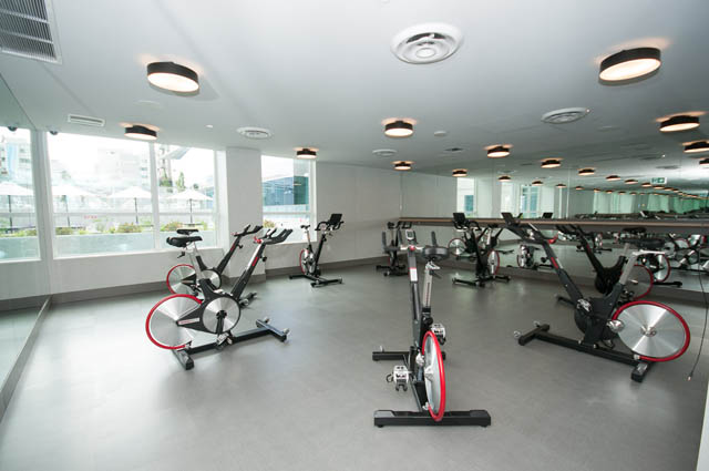 Bright gym with modern equipment and large windows, offering a city view. - 1105 - 125 E 14th St, North Vancouver
