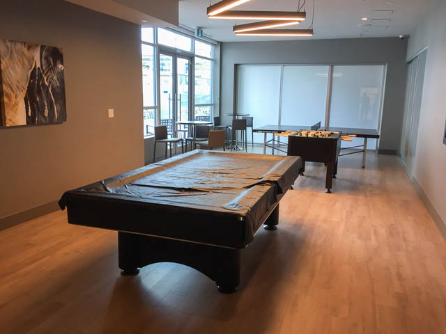 Furnished living room with pool table, hardwood floors, and city view. - 1105 - 125 E 14th St, North Vancouver